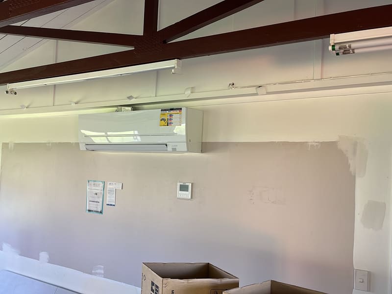 Wall-mounted heat pump and controller under exposed roof trusses