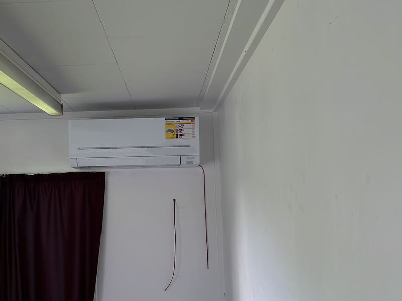 Wall-mounted heat pump installed above a window