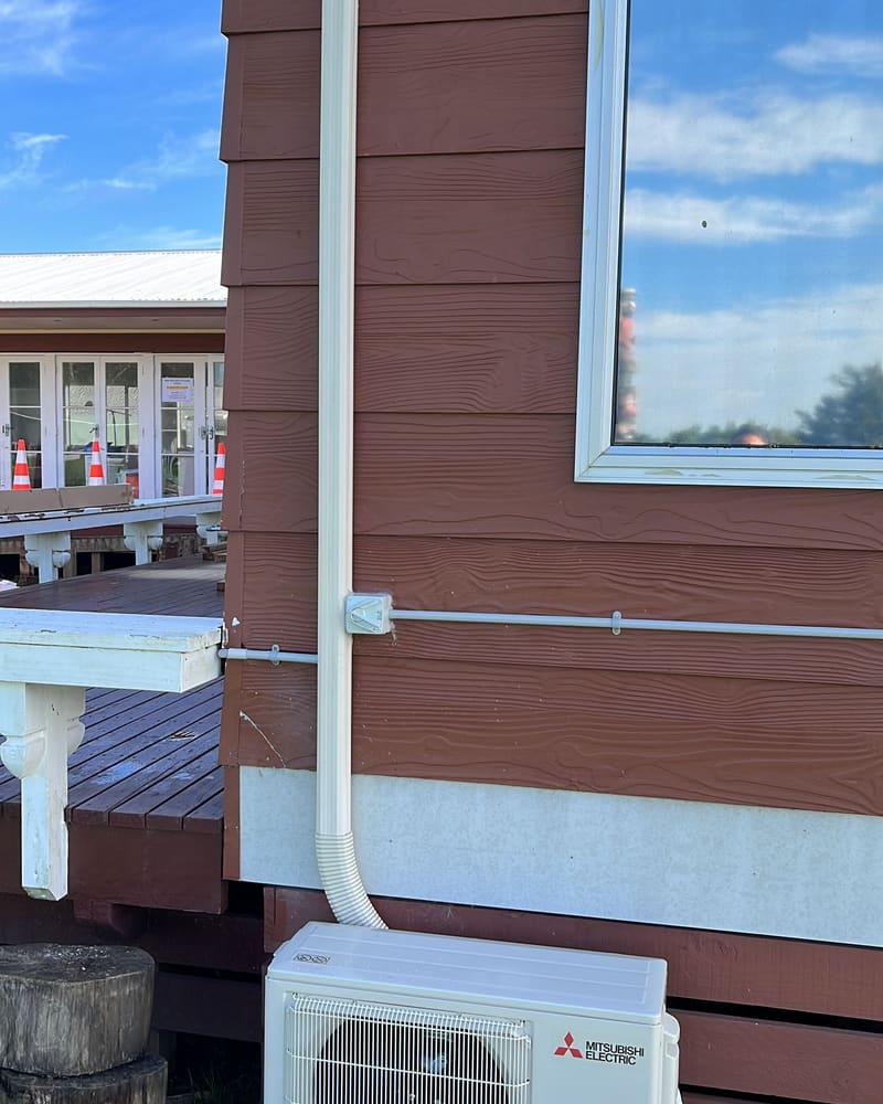 Pipe cover running along weatherboard cladding beside a deck